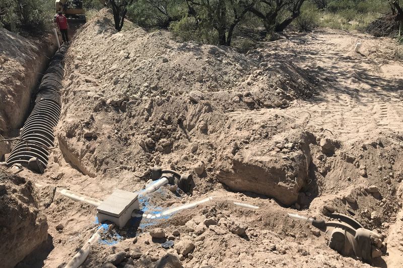 Excavated leach-field trench next to a newly placed septic tank outlet