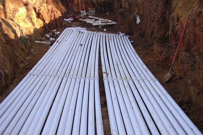 Long run of pipes laid in a red clay trench